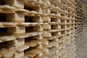 A large stack of wooden pallets is arranged in a uniform pattern, creating a repeating geometric design that reflects our commitment to meticulous services.